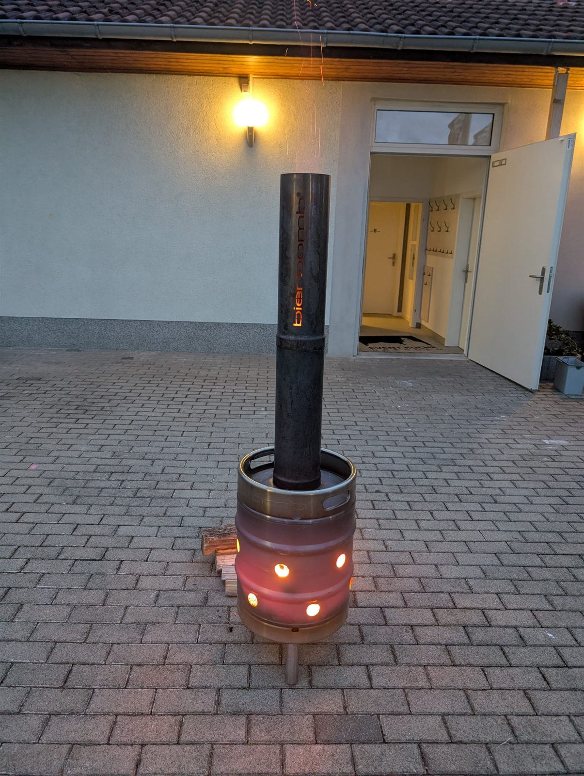 Die bierbomb Feuertonne brennt abends vor dem Eingang der Event-Küche Dresden, die Luftlöcher glühen orange
