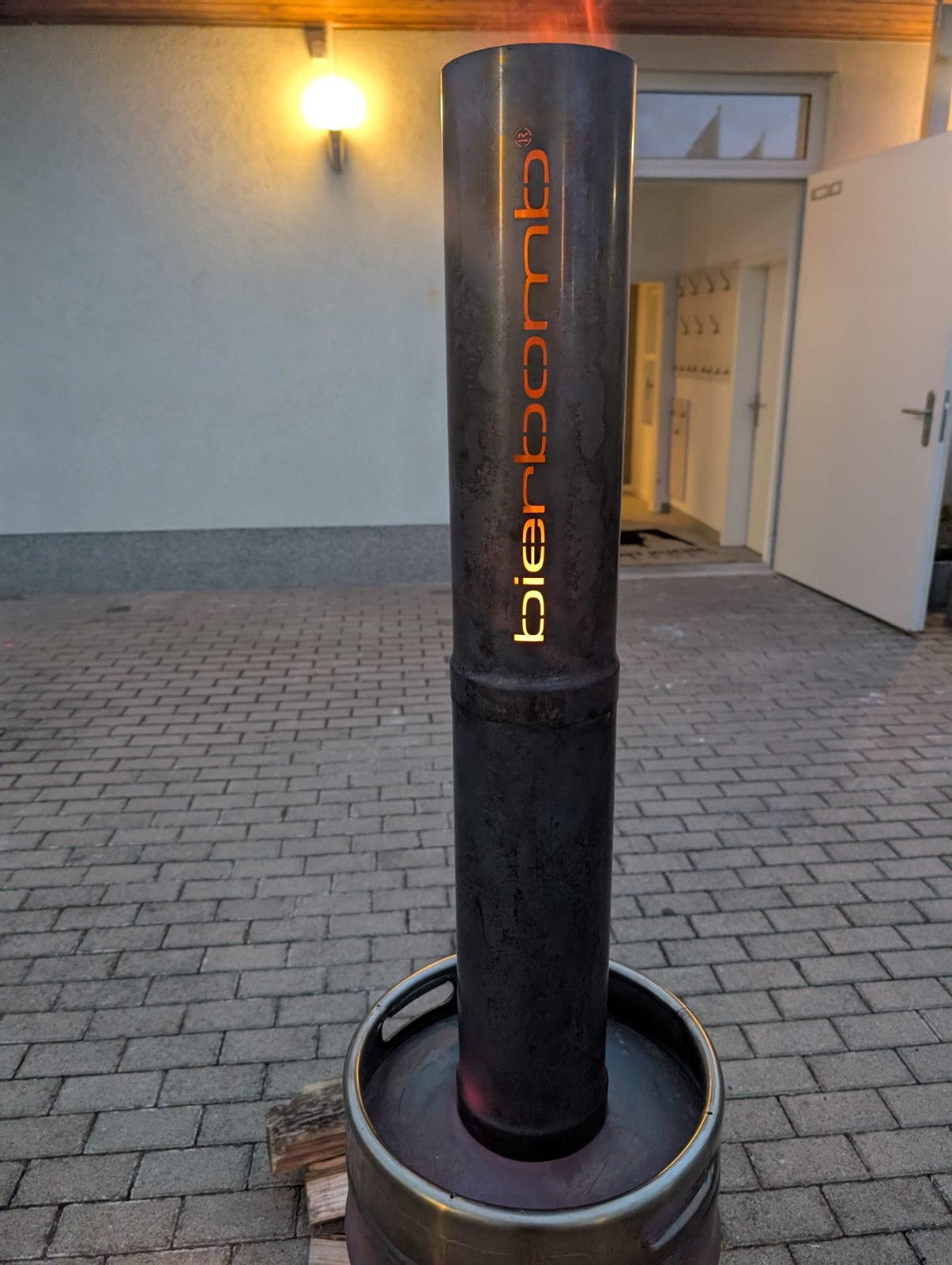 Nahaufnahme der bierbomb Feuertonne, der ins Rohr gelaserte Schriftzug glüht orange vom Feuer im Inneren