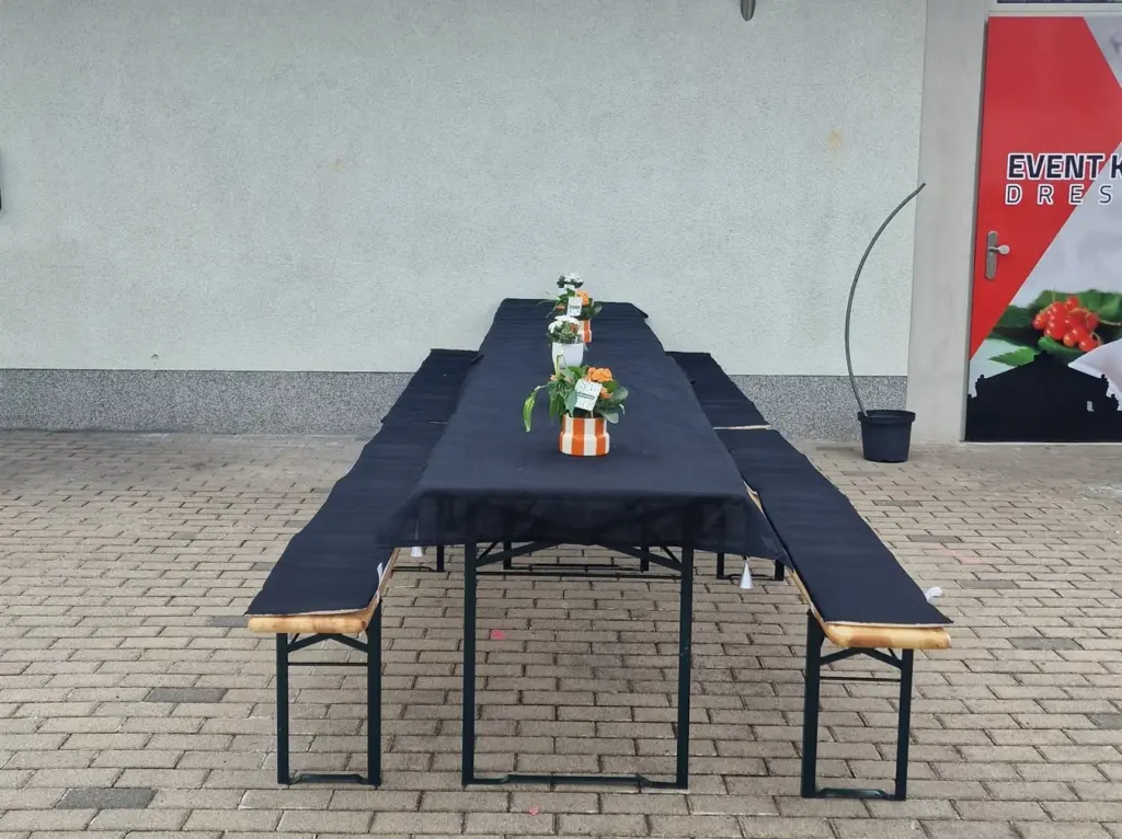Biertischgarnitur mit schwarzer Haube und Sitzpolstern im Hof vor der Event-Küche Dresden
