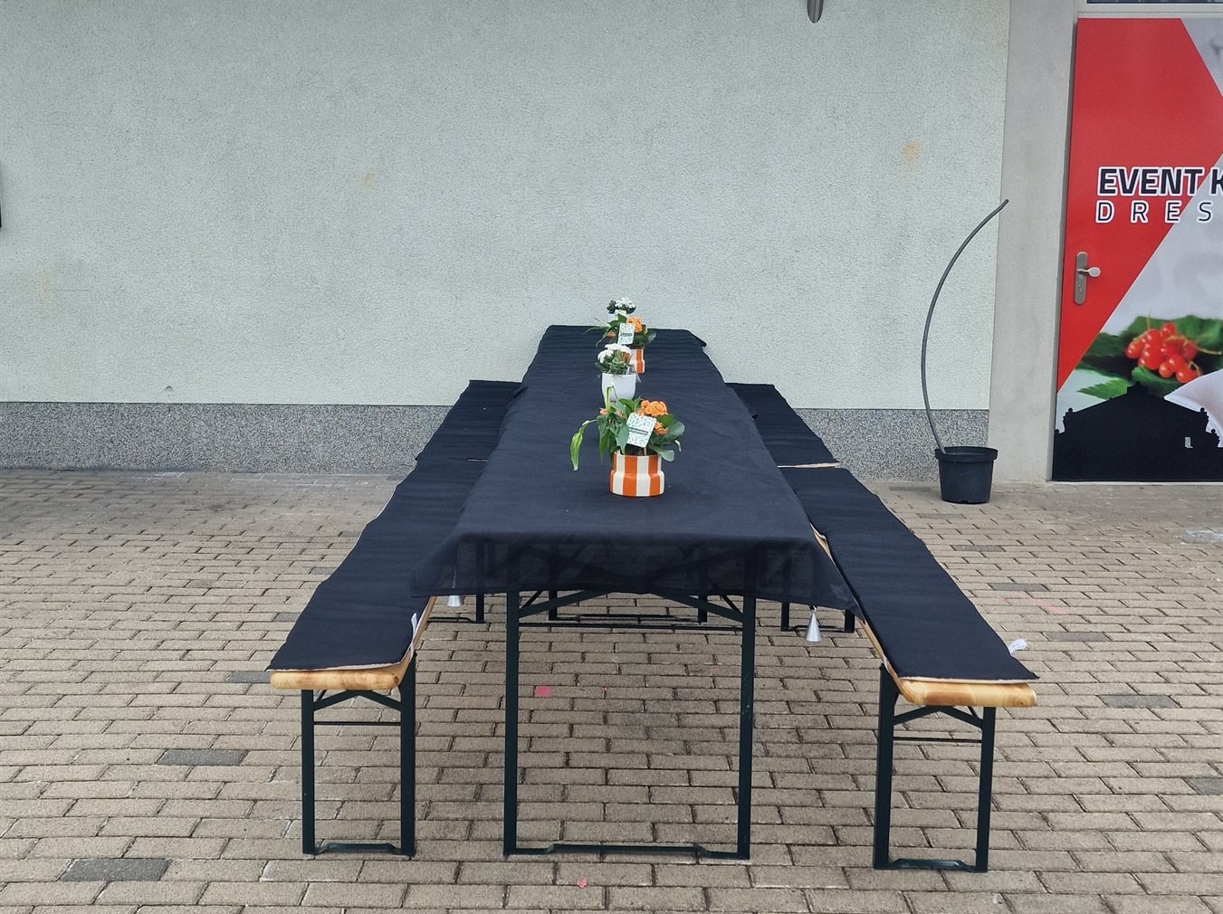 Biertischgarnitur mit schwarzer Haube und Sitzpolstern im Hof vor der Event-Küche Dresden