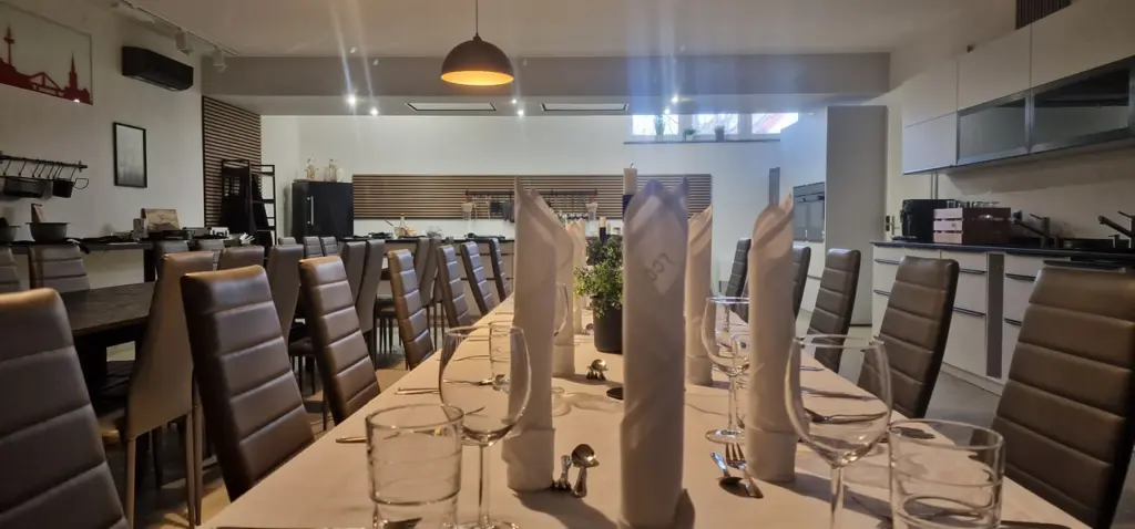Lange eingedeckte Tafel mit weißer Tischdecke, gefalteten Servietten und Gläsern