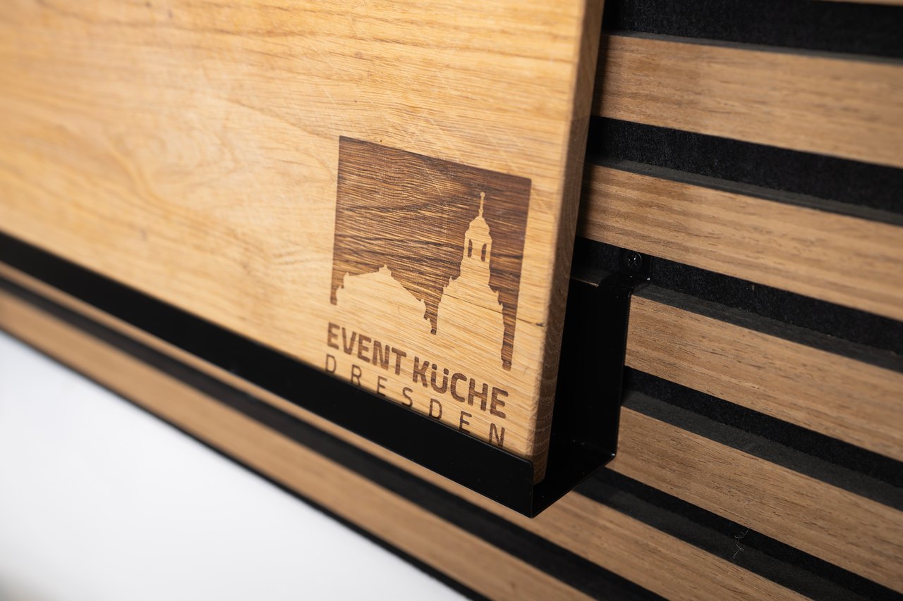 In ein Eichenbrett eingebranntes Logo der Event-Küche Dresden mit der Silhouette der Frauenkirche