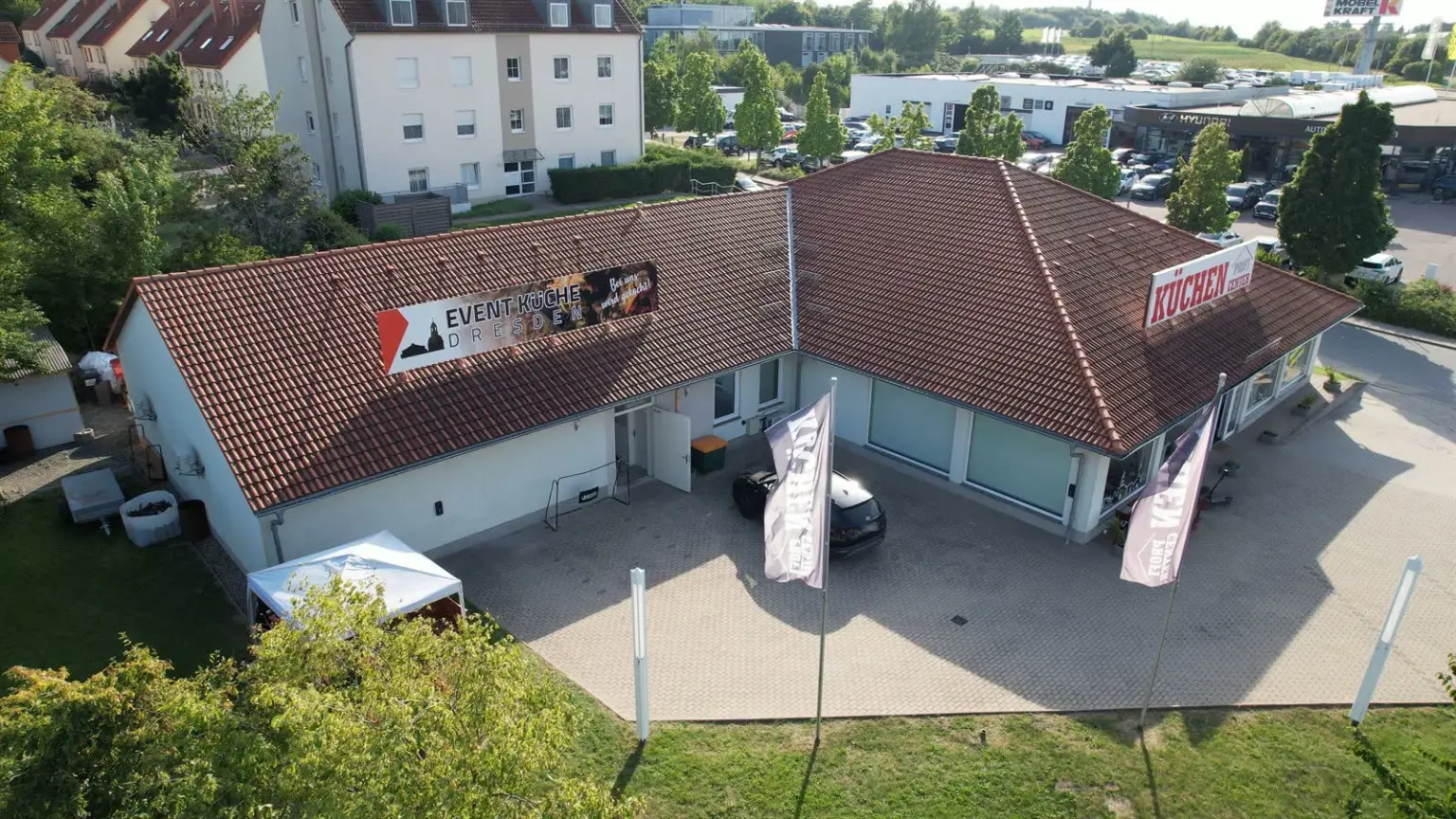Luftbild der Event-Küche Dresden: Banner auf dem Dach, gepflasterter Hof, im rechten Flügel das KüchenProfiCenter