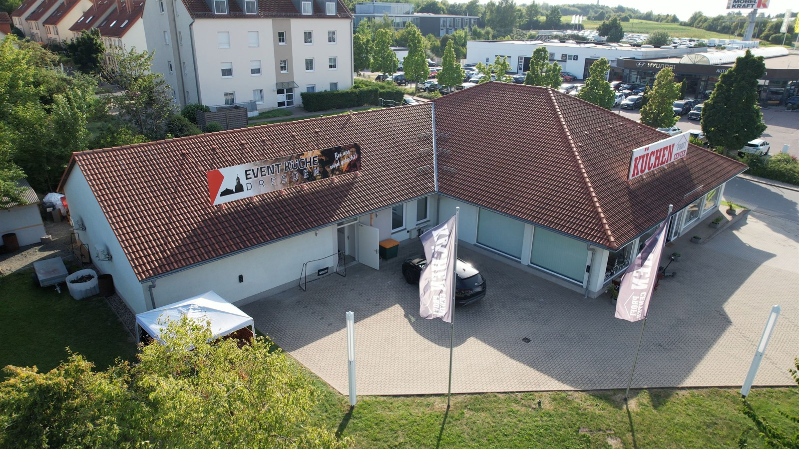 Luftbild der Event-Küche Dresden: Banner auf dem Dach, gepflasterter Hof, im rechten Flügel das KüchenProfiCenter