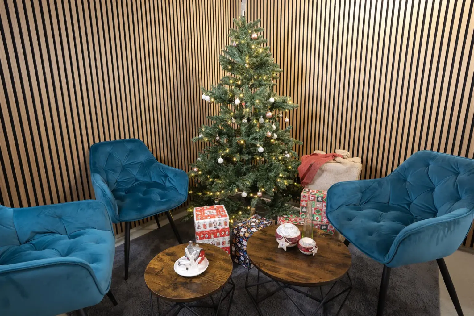 Loungeecke mit petrolblauen Samtsesseln vor dem geschmückten Weihnachtsbaum