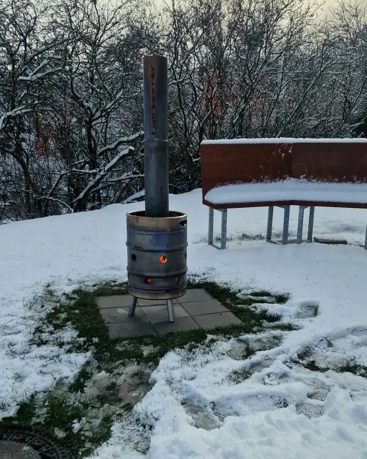 Brennende bierbomb Feuertonne im Schnee vor der Event-Küche Dresden, daneben eine Sitzbank aus Cortenstahl