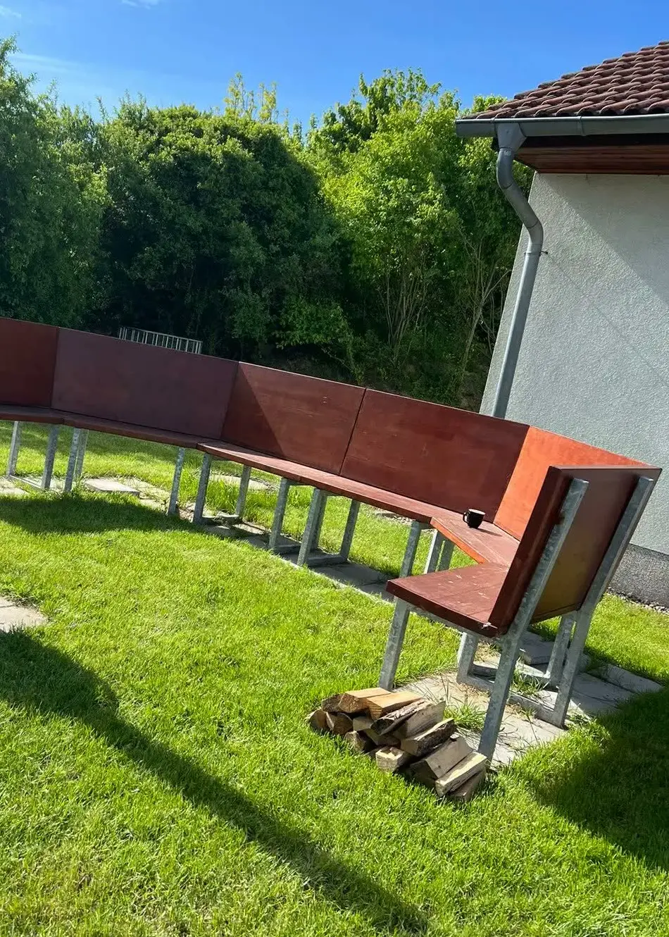 Der Rasen neben der Event-Küche Dresden im Sommer, davor eine lange geschwungene Sitzbank aus Holz