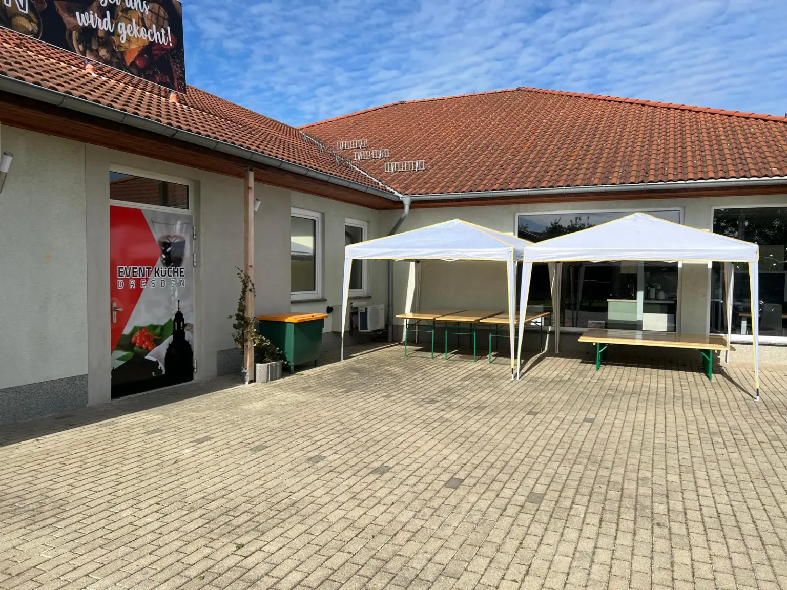 Zwei weiße Pavillons mit Biertischgarnituren auf dem gepflasterten Hof der Event-Küche Dresden